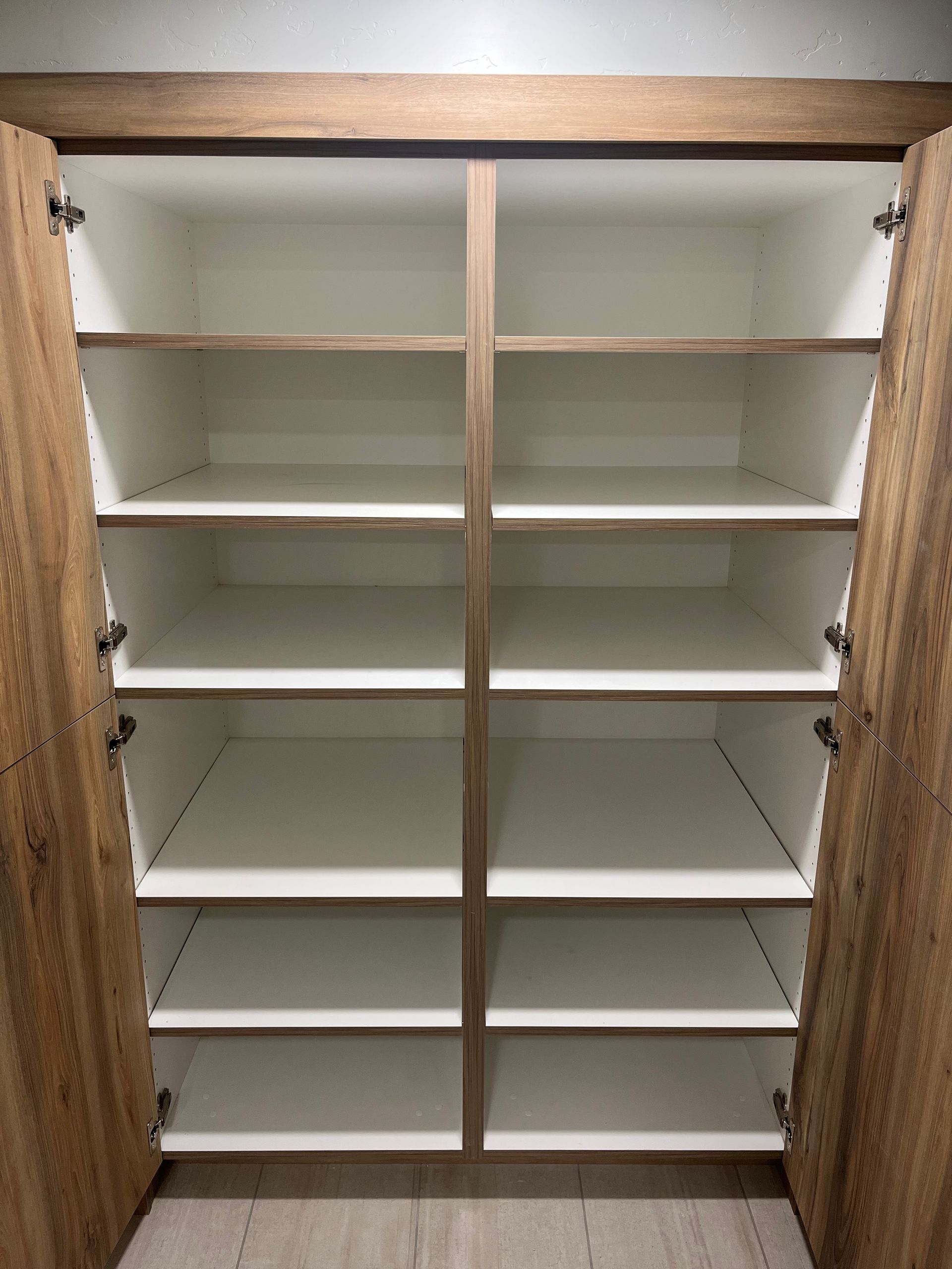 Open cabinet with white shelves and wood doors, showing empty storage compartments