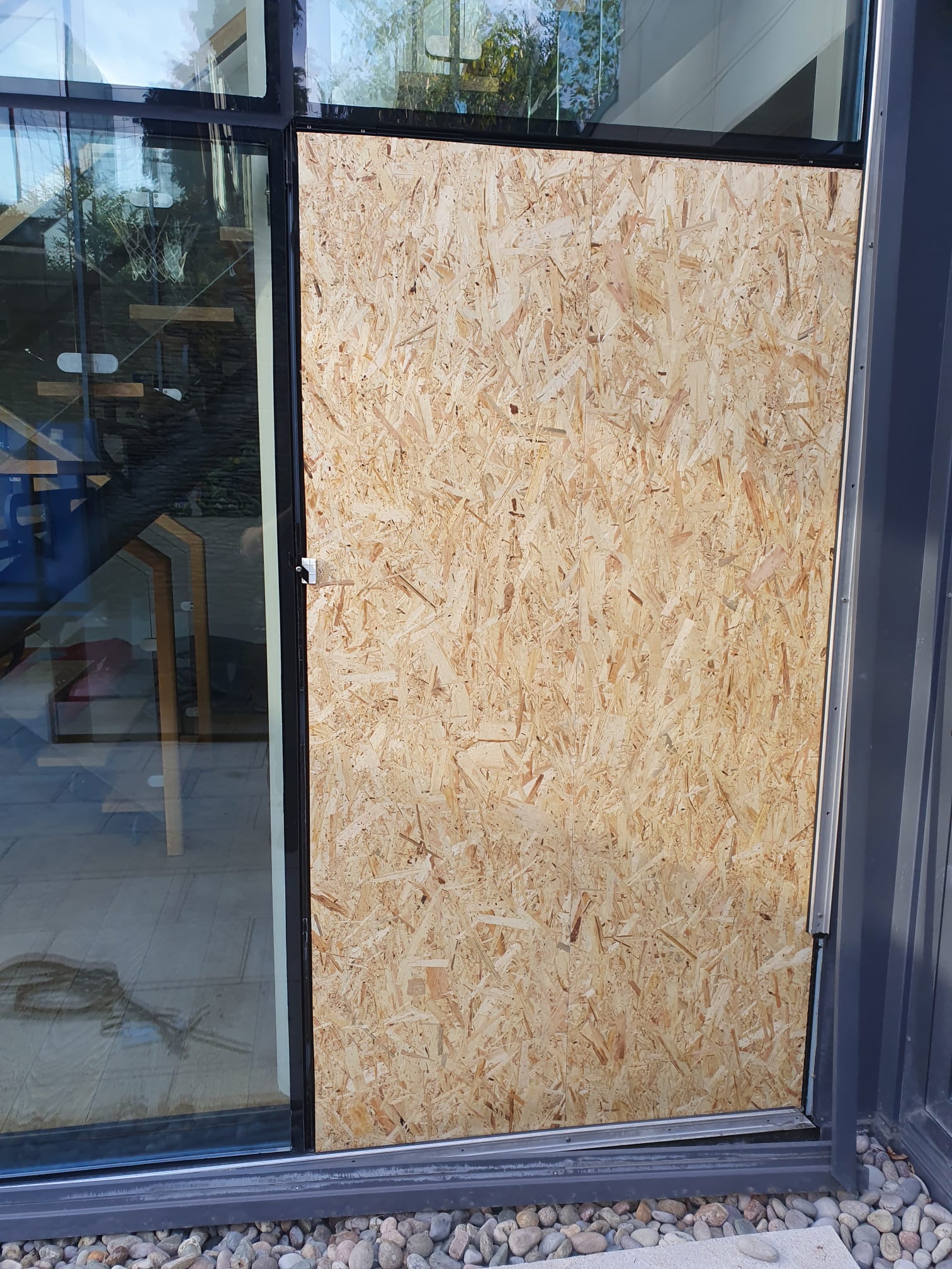 A window with a piece of plywood covering it.