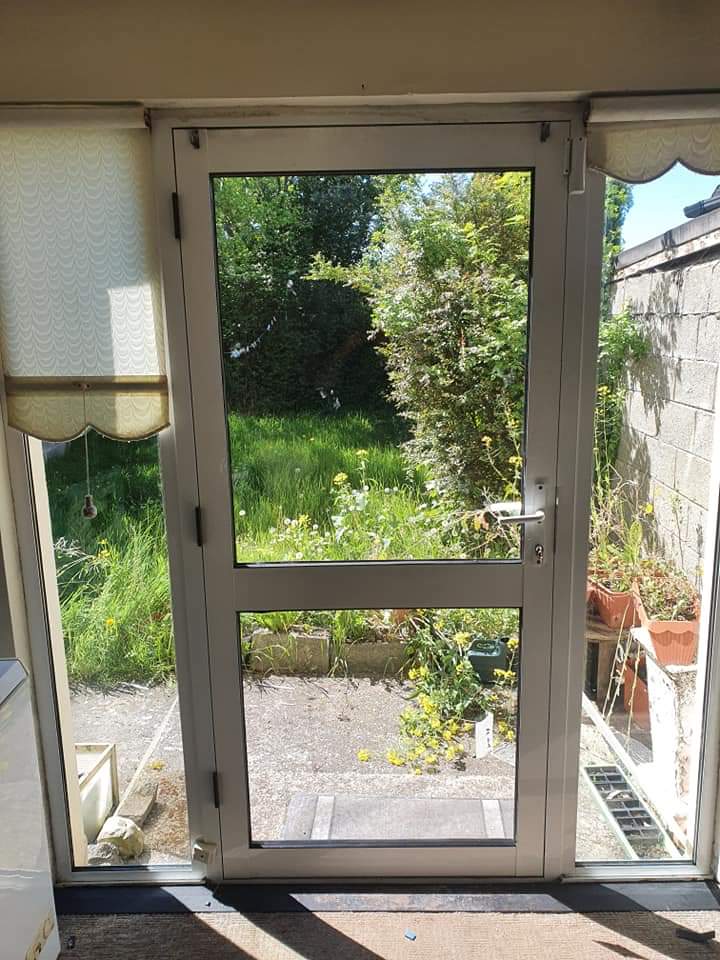 A white door with a view of a garden through it.