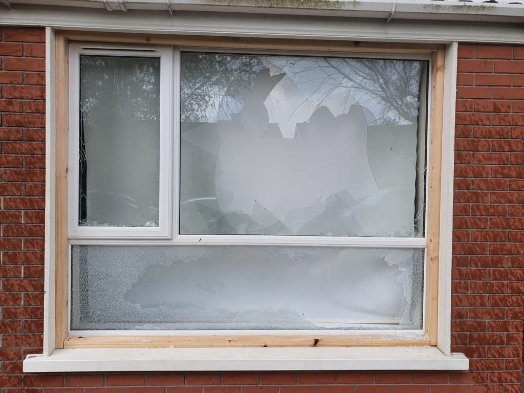 A broken window is sitting on a brick wall.