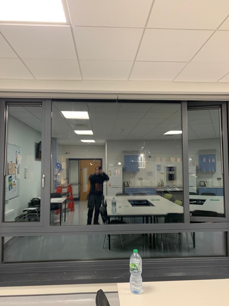A man is standing in a room with a bottle of water on a table.