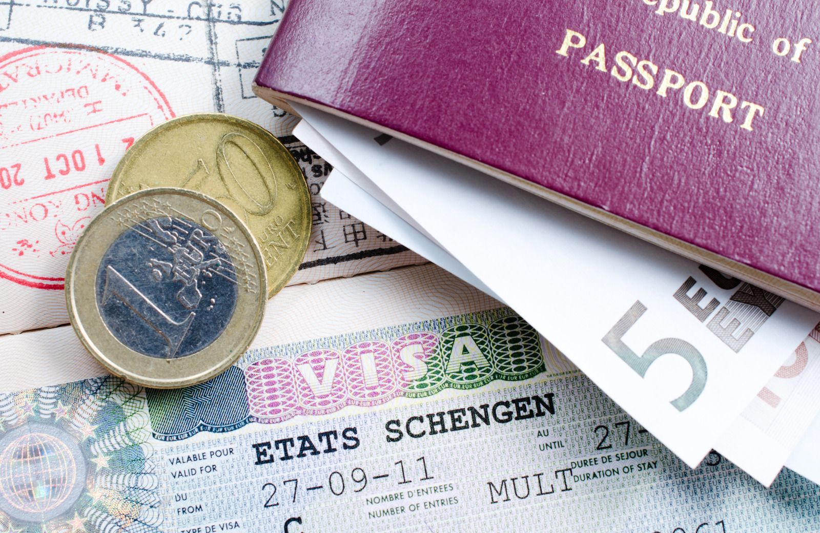 Passport, visa, Euro coins and banknotes on a background of stamps.