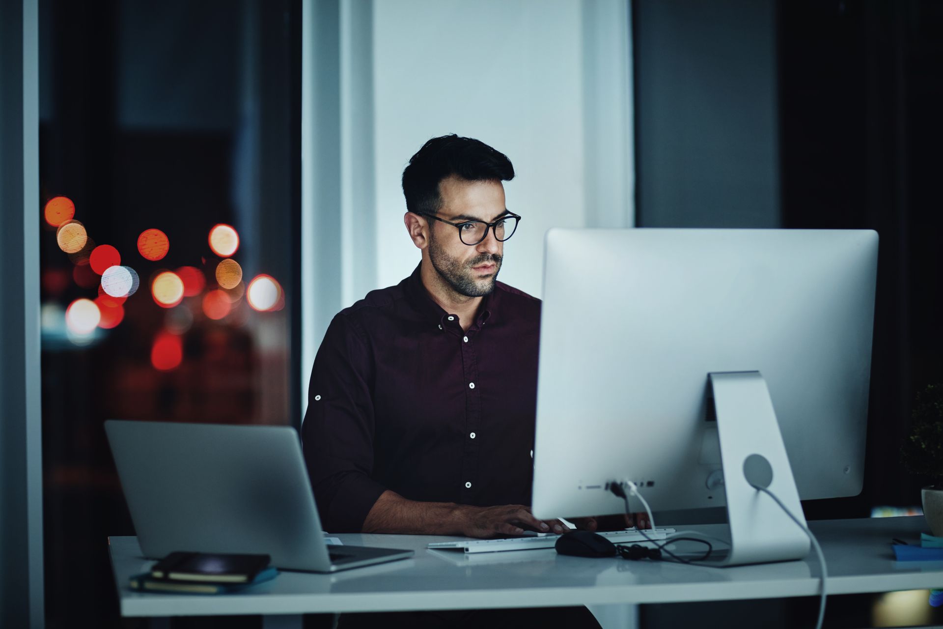 A man is sitting at a desk using a laptop and a tablet.