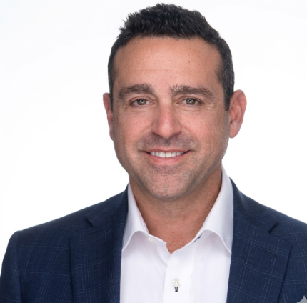 A man in a suit and white shirt smiles for the camera