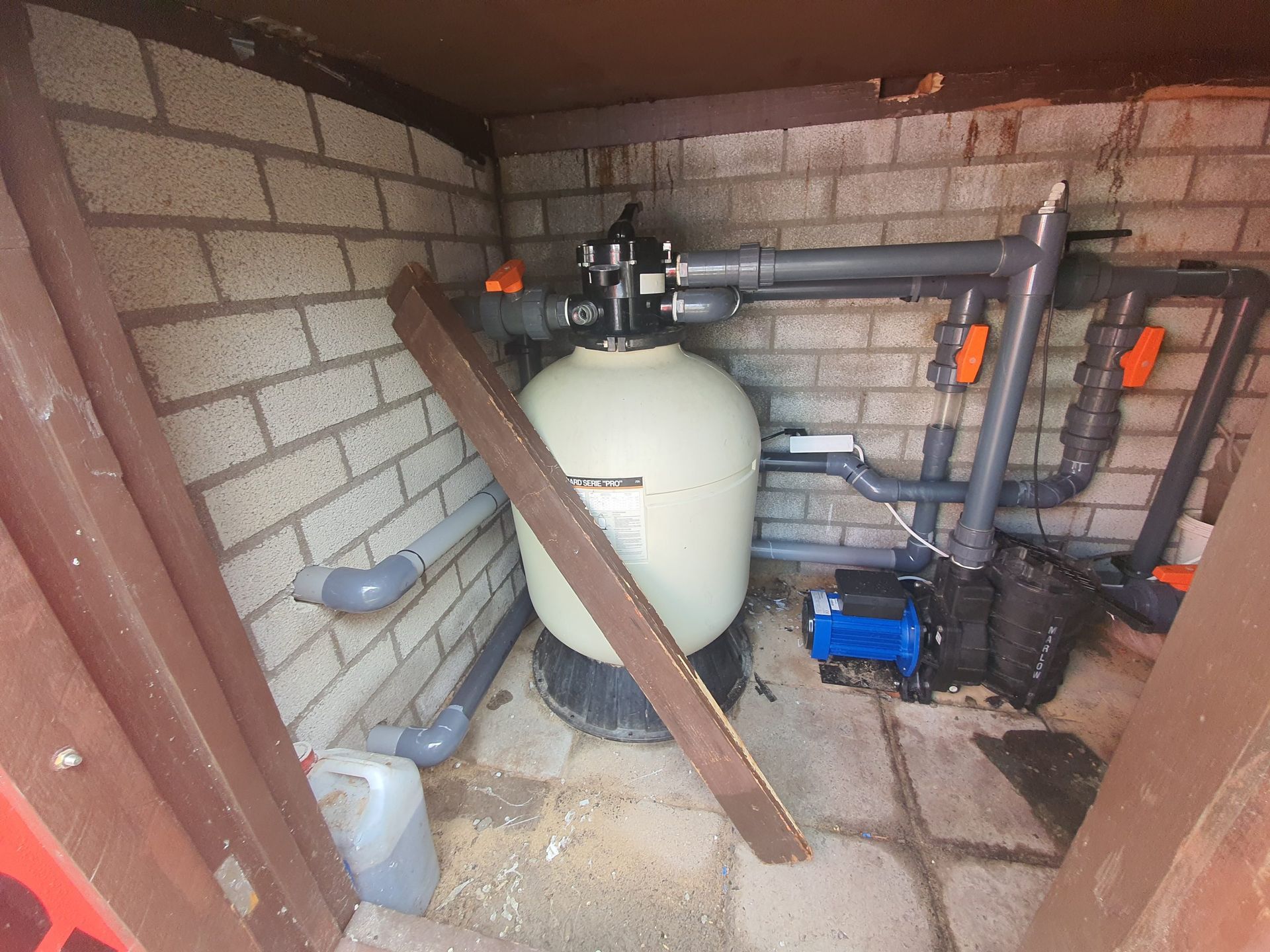 Een zwembadfilter bevindt zich in een bakstenen gebouw.