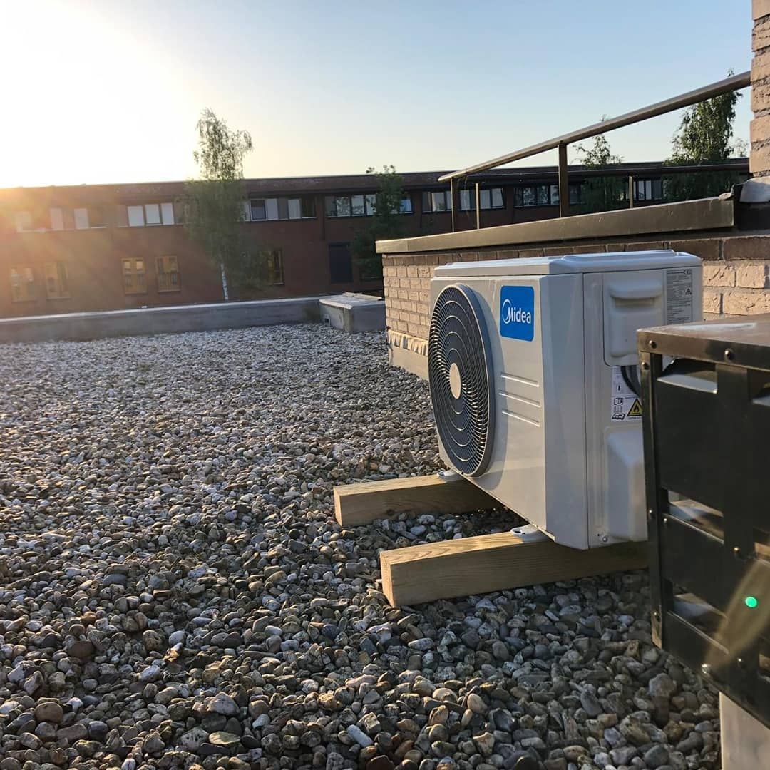 Een witte airconditioner staat bovenop een stapel grind.