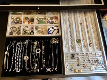 Jewelry drawer with necklaces, bracelets, and small items organized in compartments.