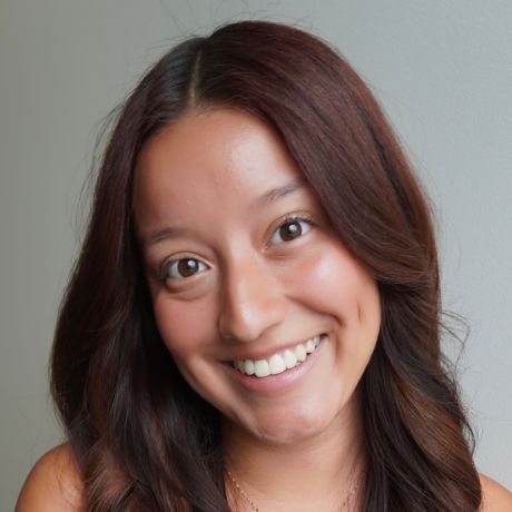Woman with auburn hair smiles in front of a wooden wall, wearing a black top.