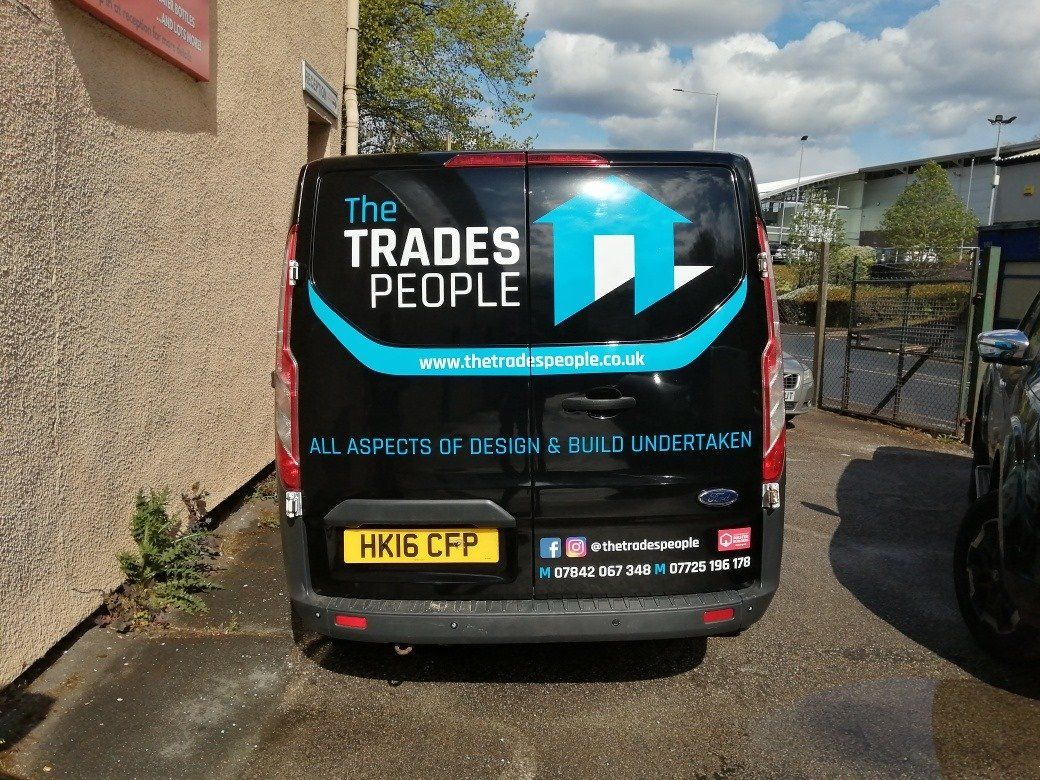 The trades people van is parked in front of a building
