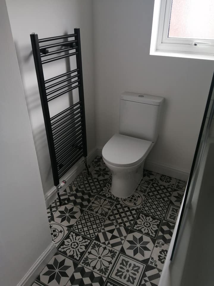 A bathroom with a toilet , towel rack and window.