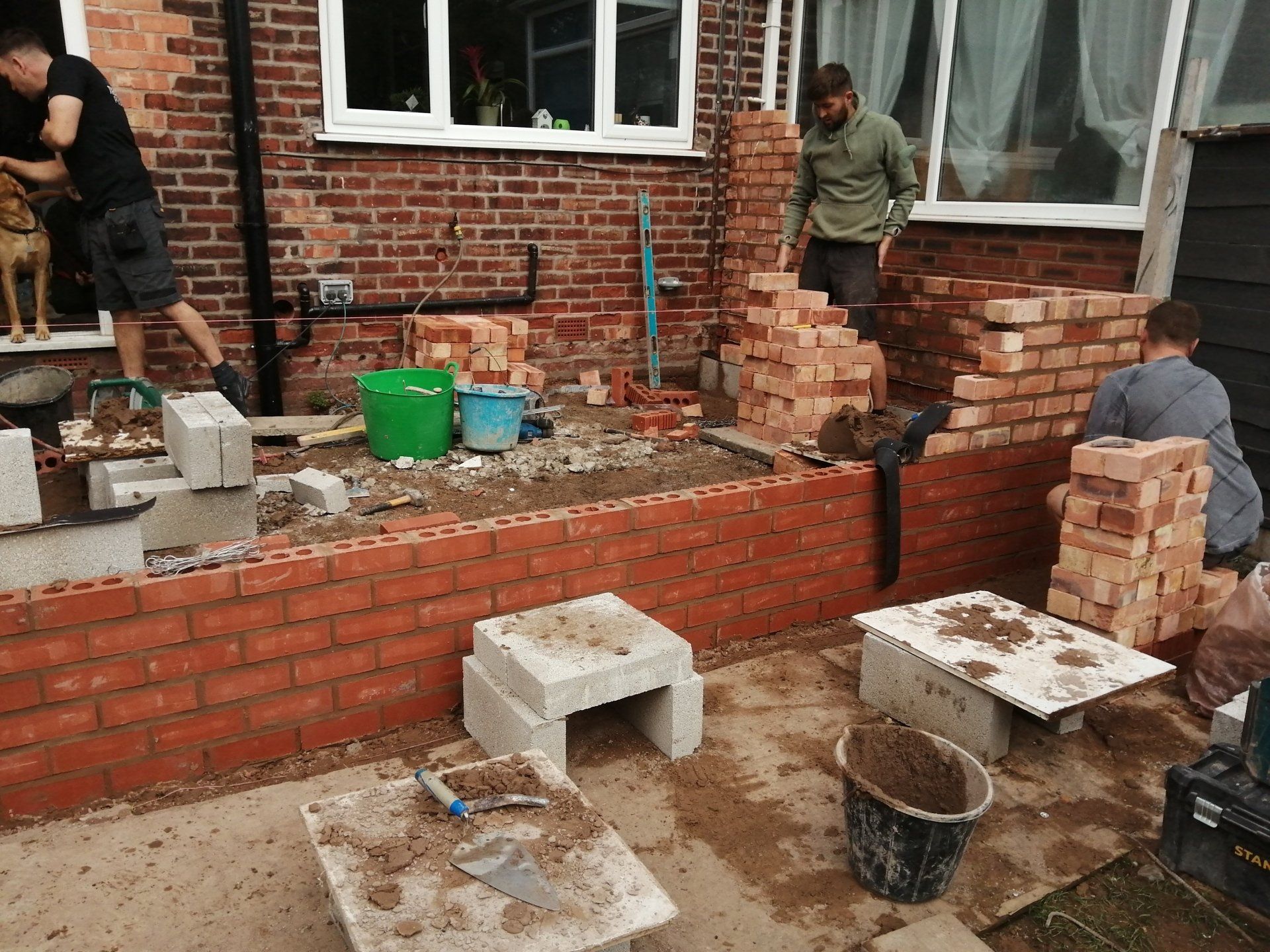 A group of men are working on a brick wall.