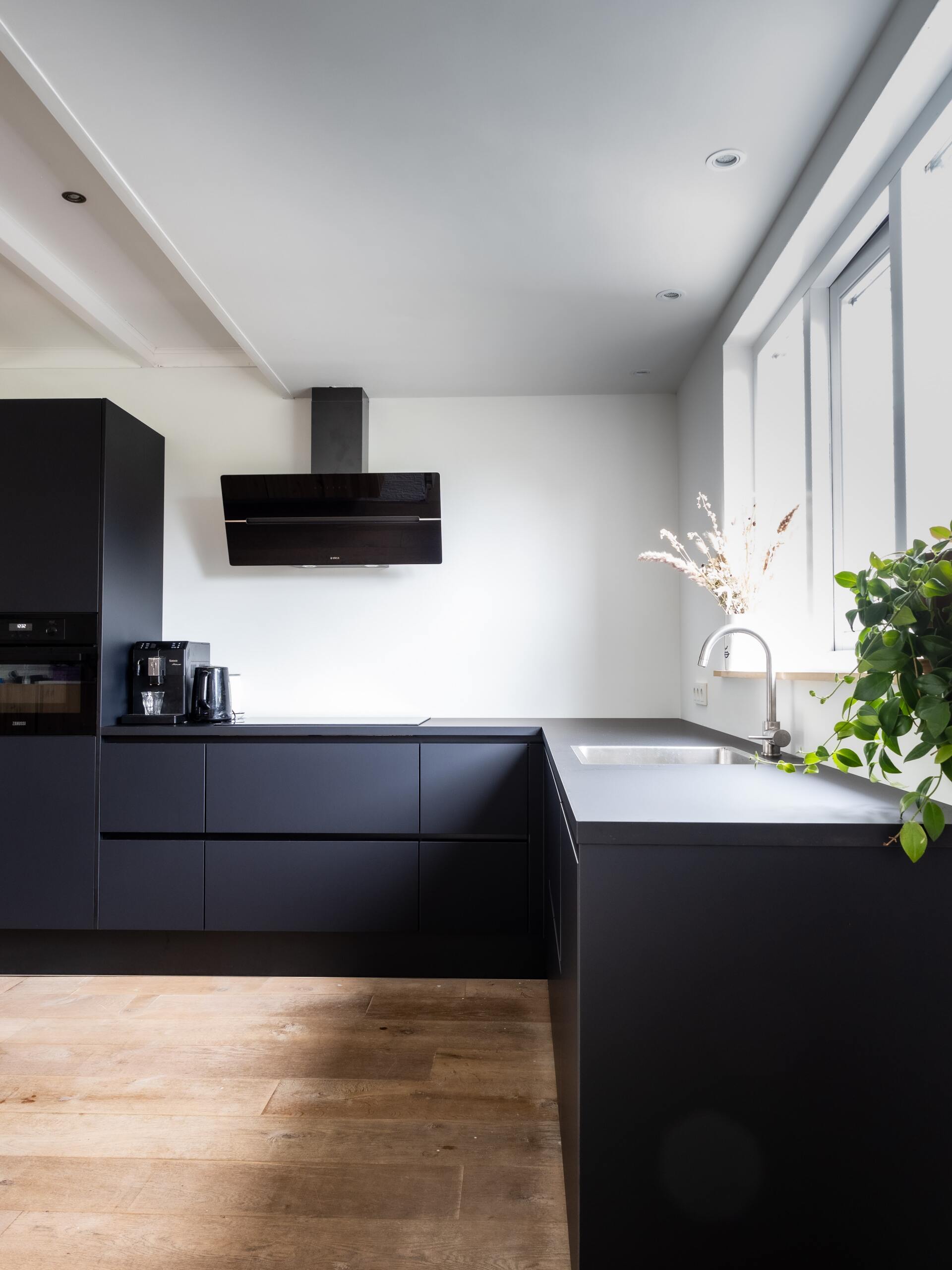 A kitchen with black cabinets , a sink , and a window.