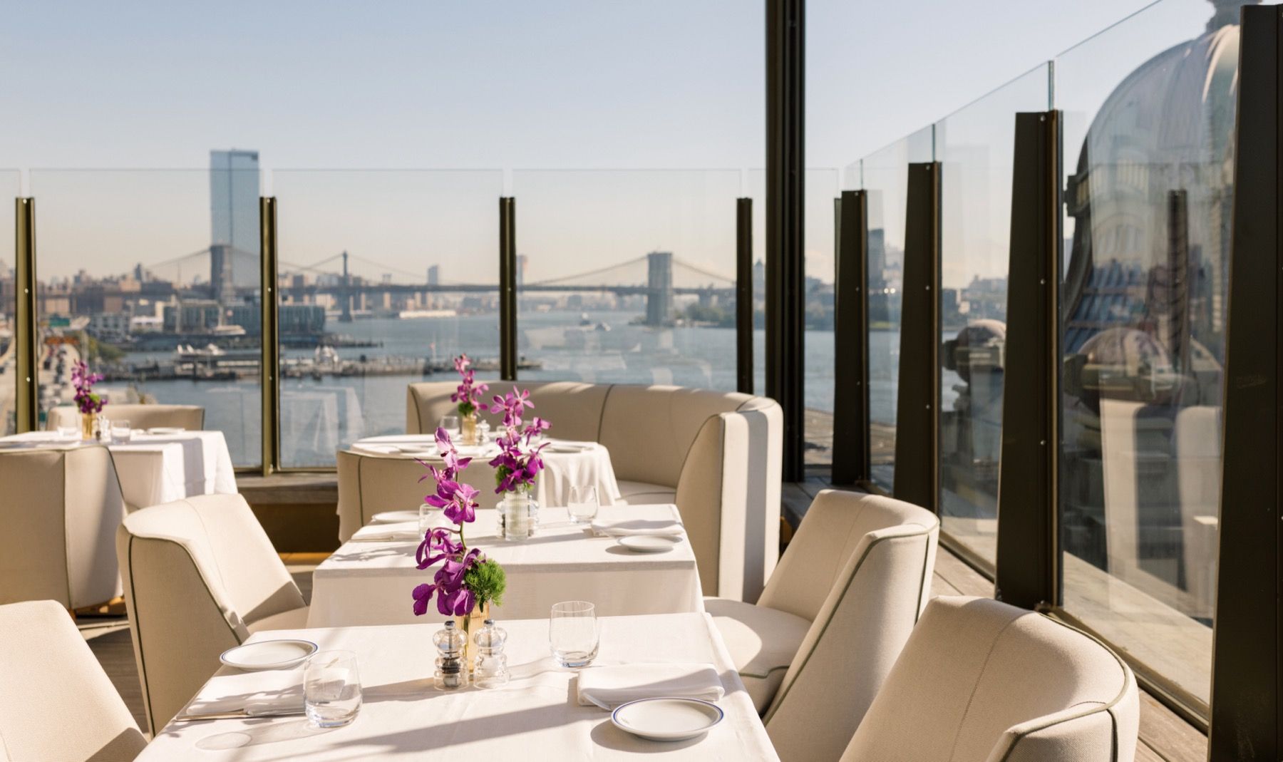 A restaurant with tables and chairs and a view of the city.