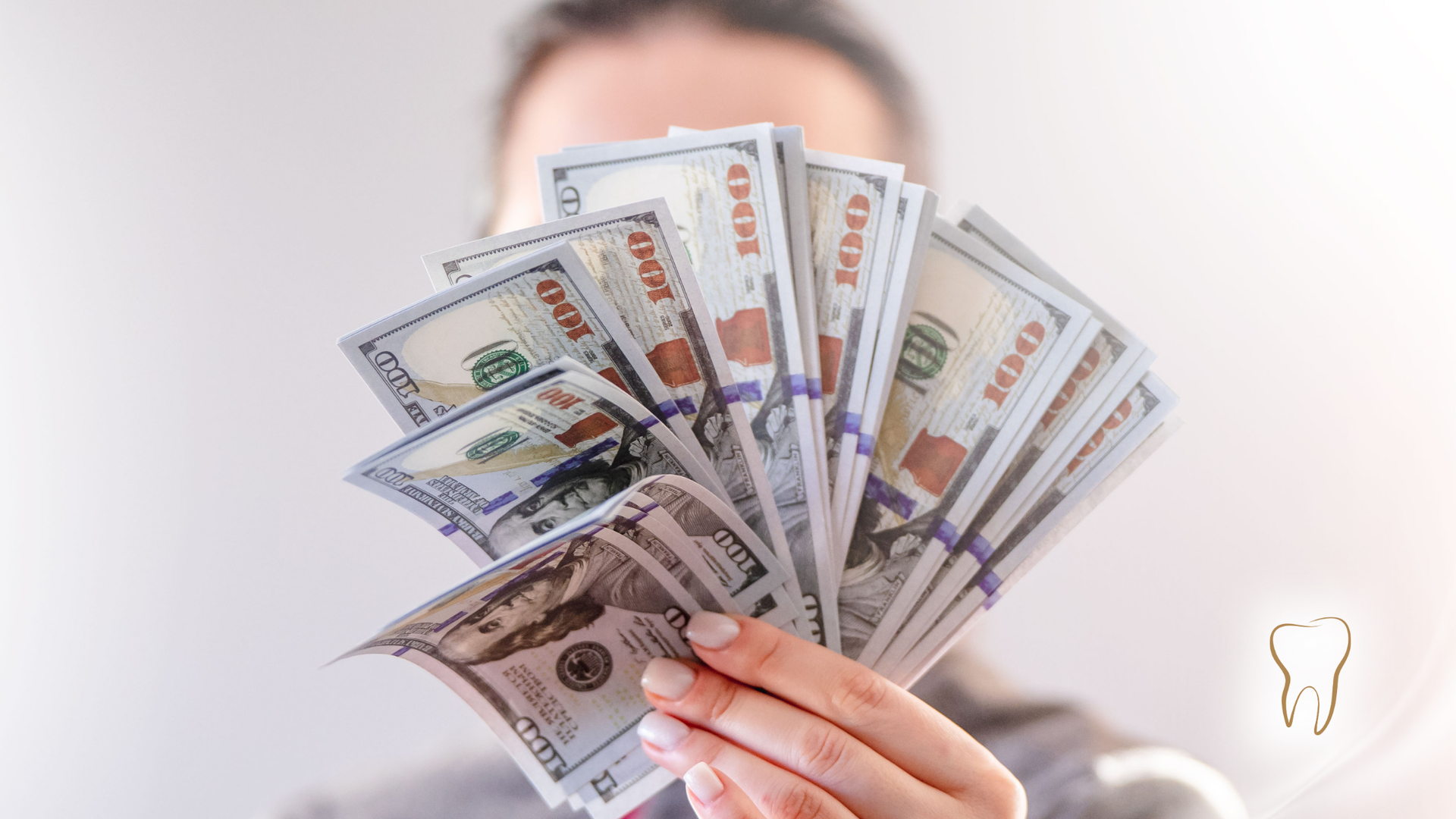 Person holding a large stack of $100 bills in their outstretched hand.