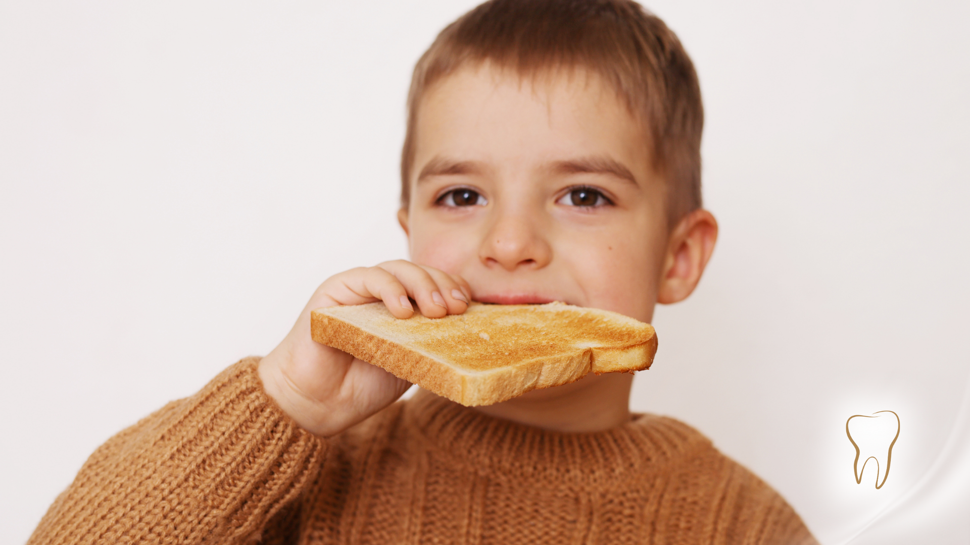 Boy eating a piece of toasted bread, smiling.
