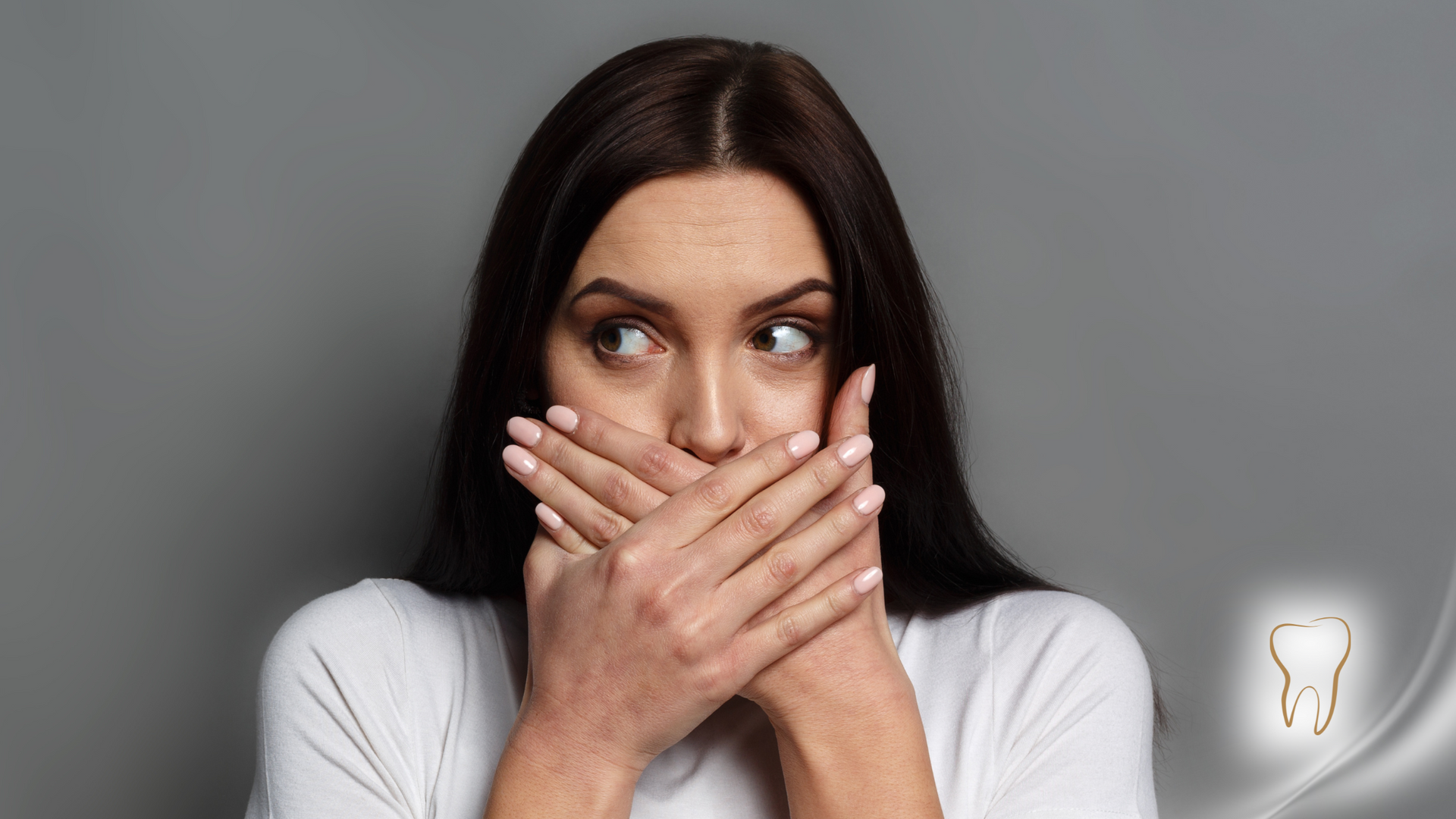 Woman covering mouth with hands, eyes wide, reacting with surprise.