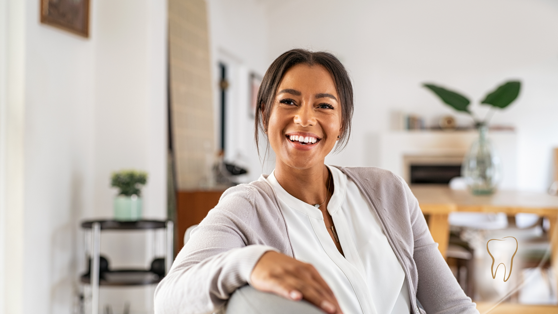 Woman smiling indoors, blurred background of a living area.