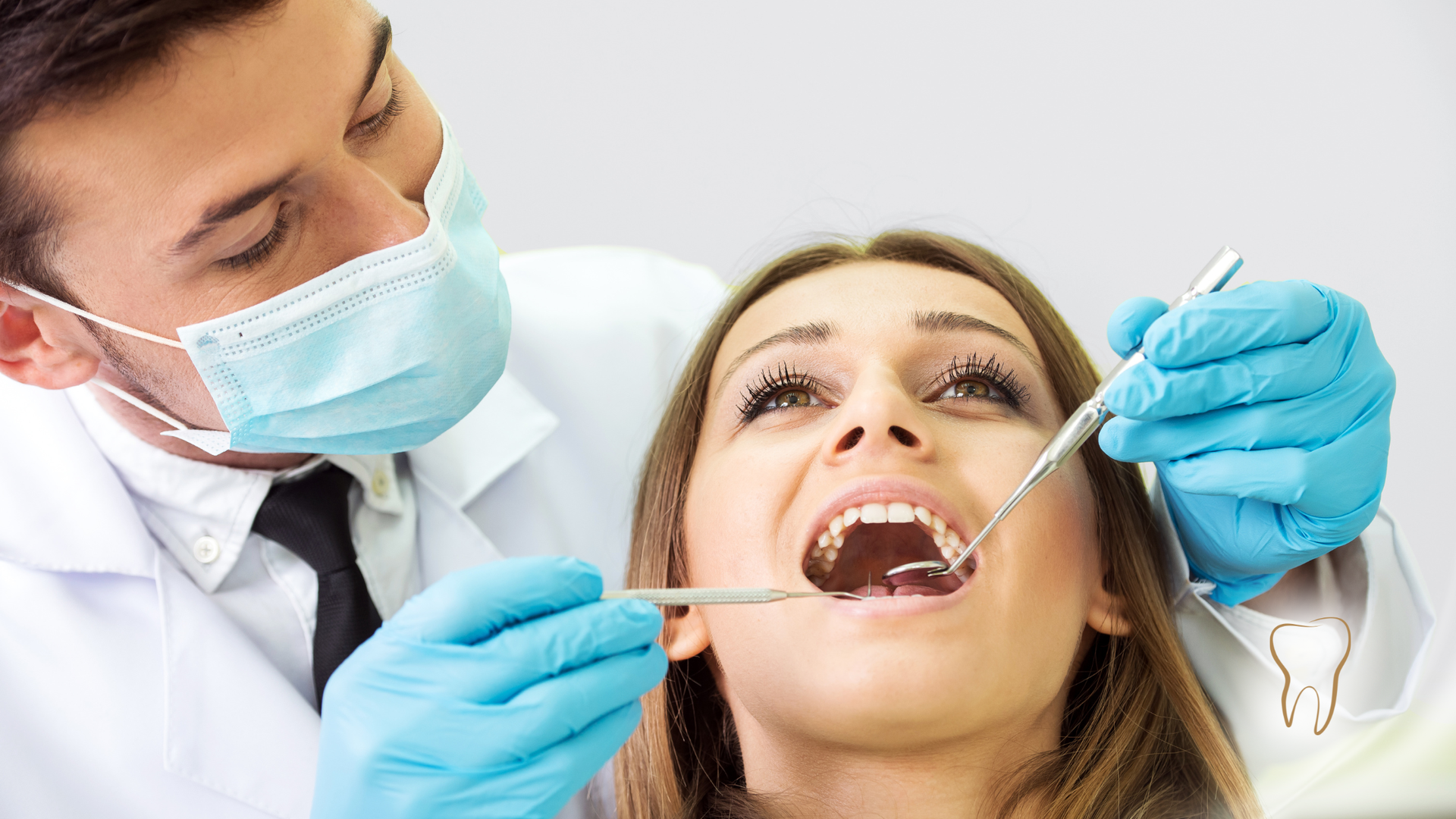 Dentist examining a patient's teeth with tools in a dental office. The patient has mouth open.