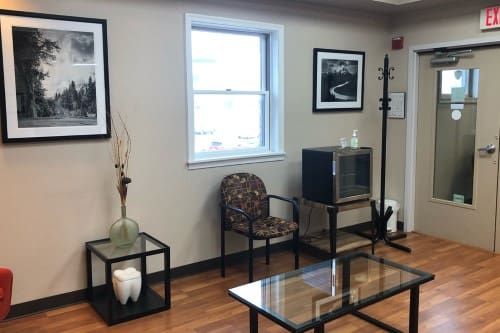 A waiting room with chairs , a coffee table , and a television.