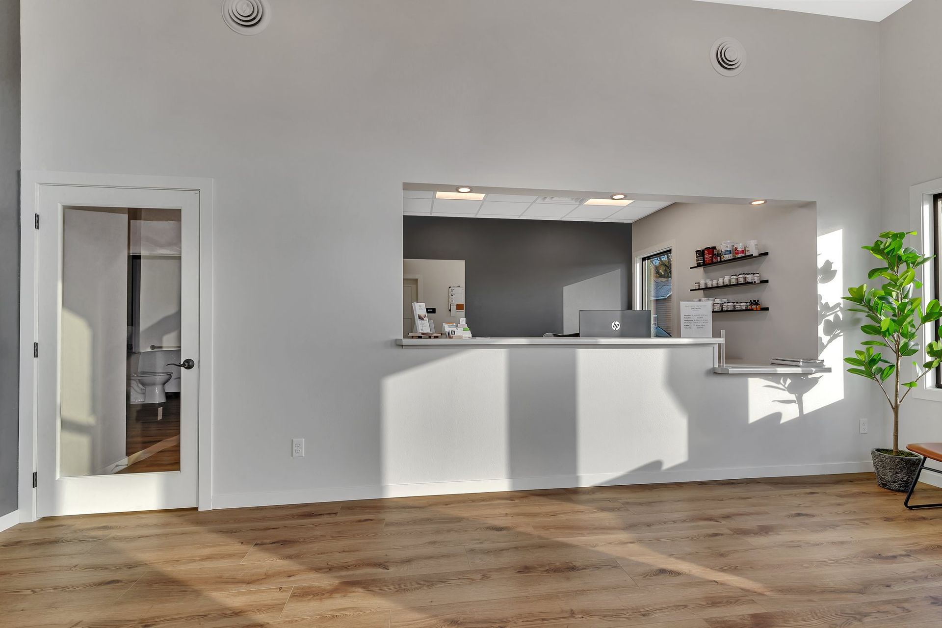 Interior shot of a reception area with a white counter, hardwood floors, and a glass door.