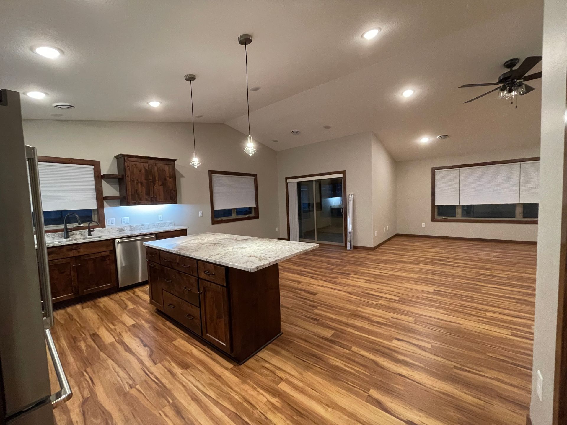 Kitchen with dark wood cabinets, island, and wood floors. Sunlight streams through the windows.