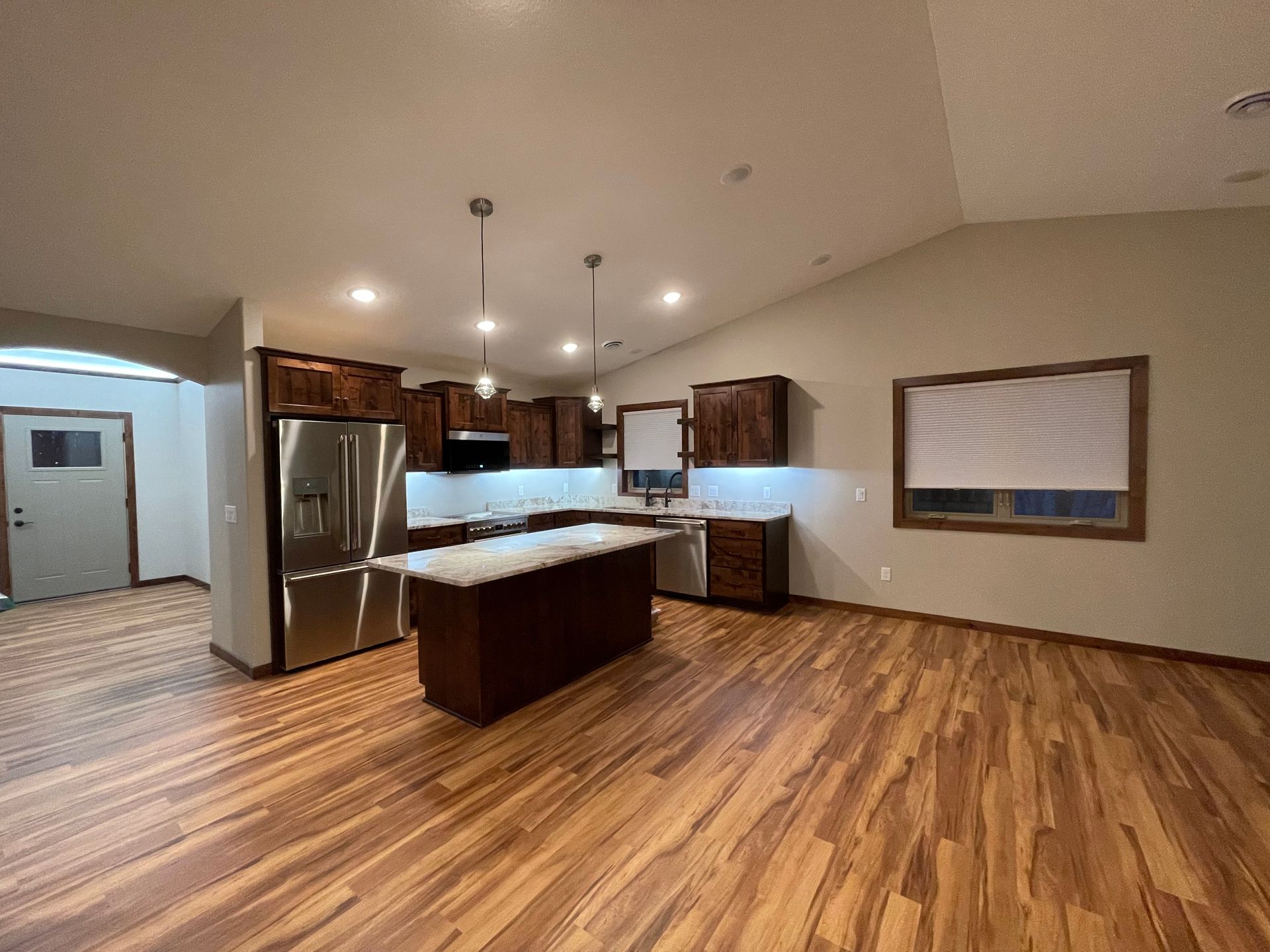 Kitchen with dark wood cabinets, stainless steel appliances, and wood flooring.