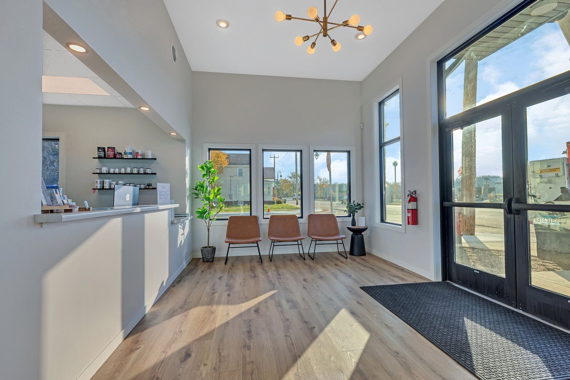 Modern office waiting room with chairs, a reception desk, and large windows.