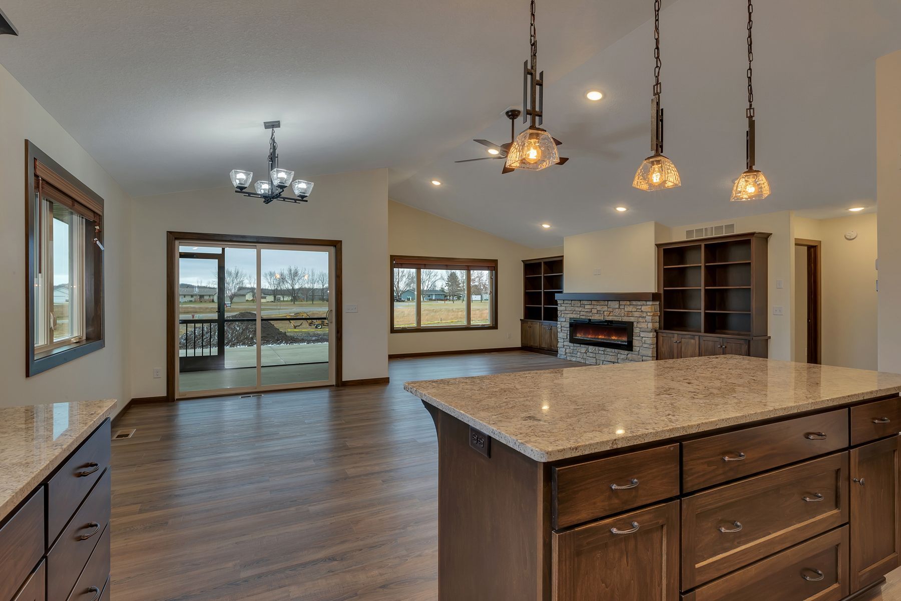 Open-concept living space with kitchen island, fireplace, and sliding glass doors to a deck.