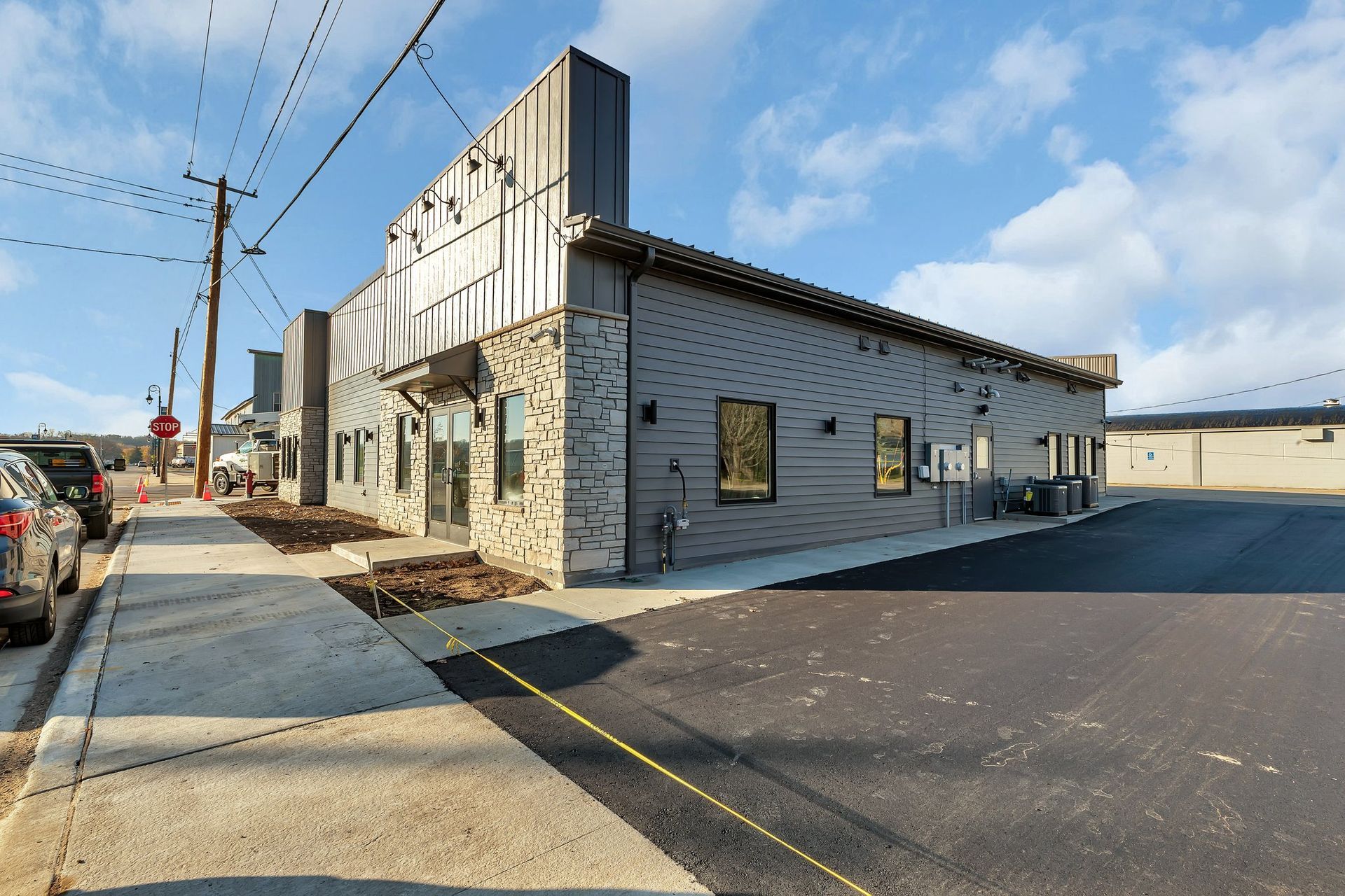 Modern building with gray siding, stone accents, and dark windows, on a city street.
