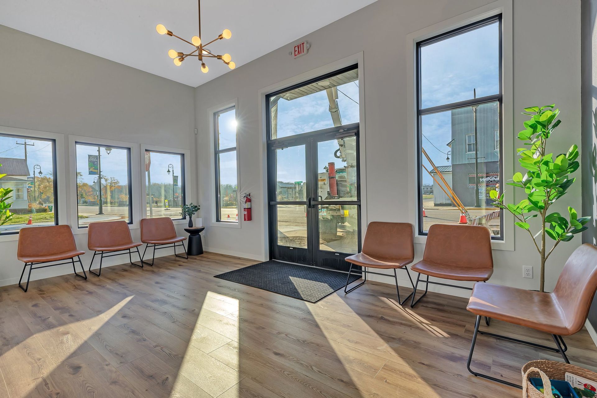 Waiting room with brown chairs, large windows, and a modern light fixture.
