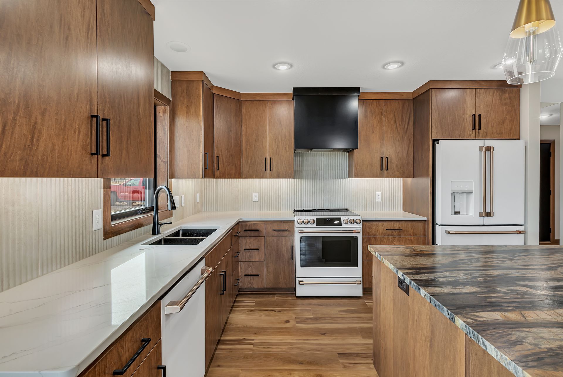 Modern kitchen with wood cabinets, white appliances, and a large island countertop.