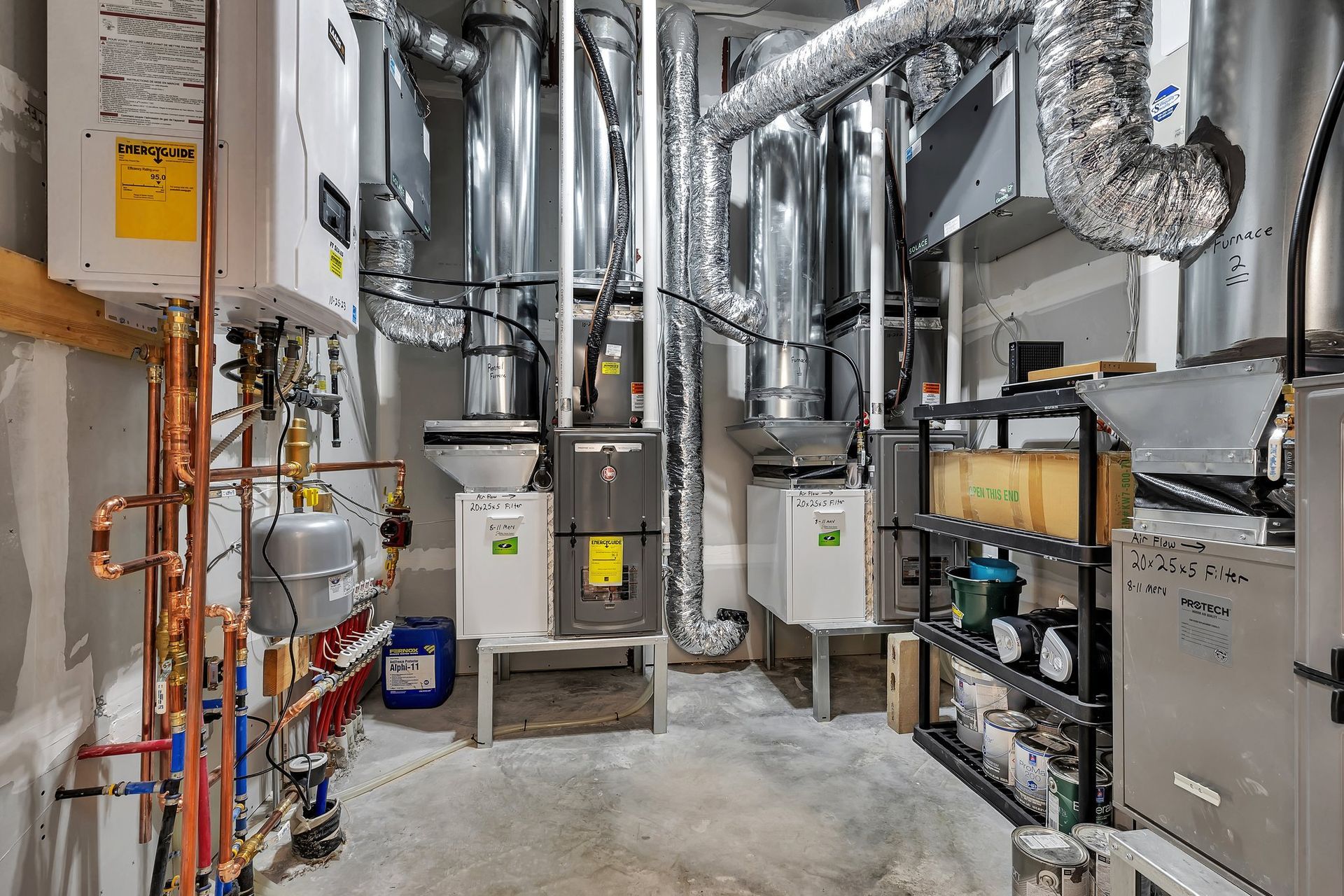 HVAC systems in a basement: furnaces, ductwork, piping, and shelving with supplies.