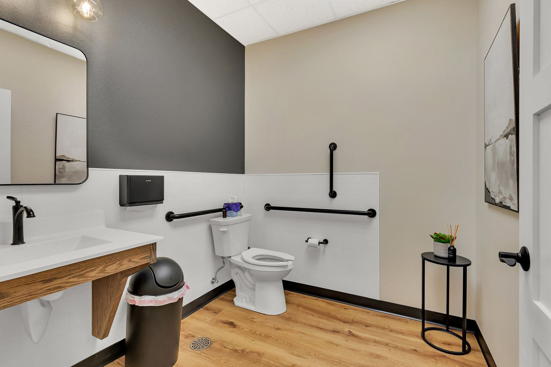 Accessible restroom with a toilet, sink, and safety bars. Tan and black color scheme.