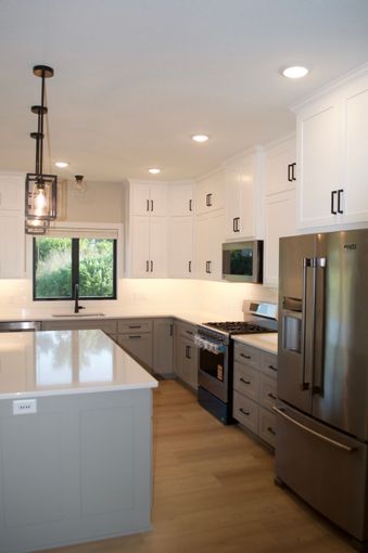 Bright modern kitchen with white cabinets, gray island, stainless steel appliances, and a window over the sink