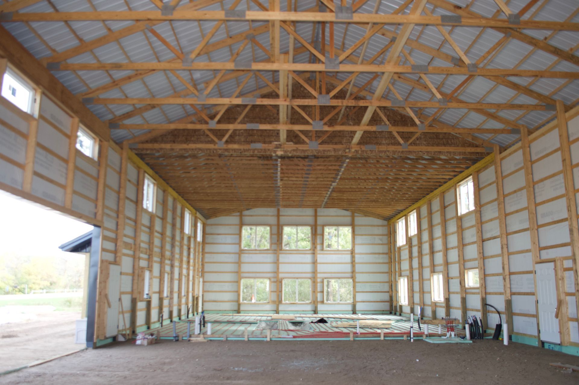 Interior of an unfinished wooden barn with exposed trusses and open wall framing