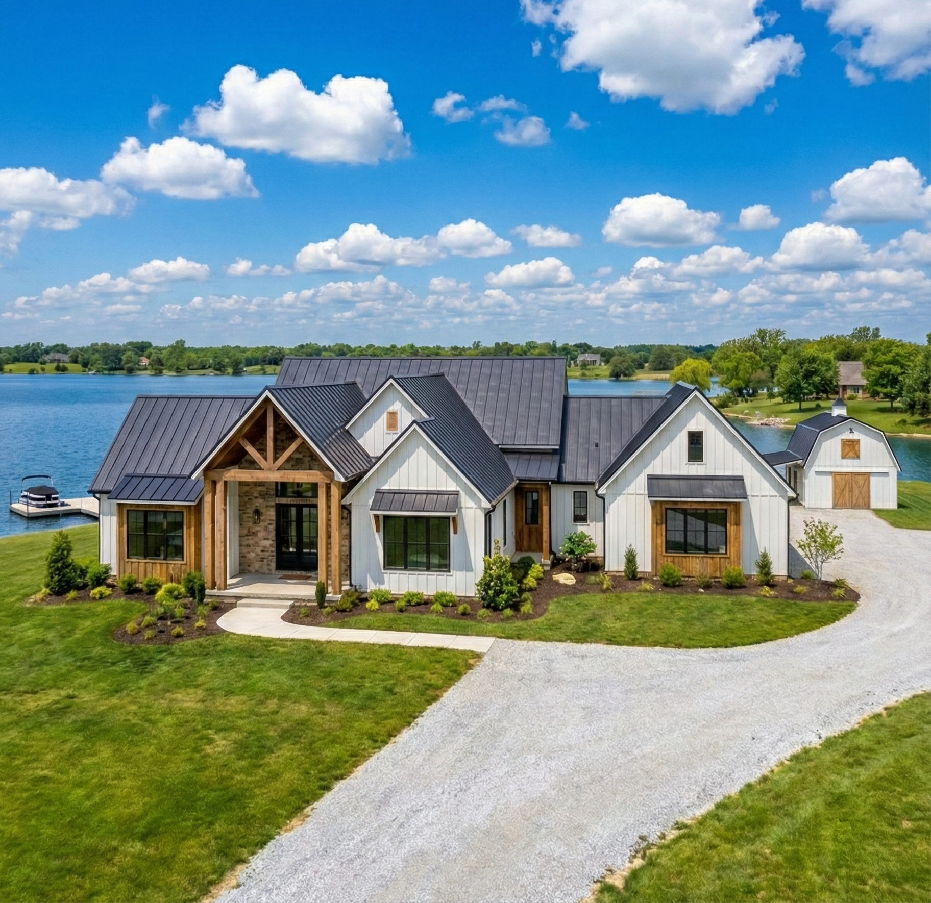 Modern lakeside house with dark roofs, white walls, and a curved gravel driveway under a blue sky