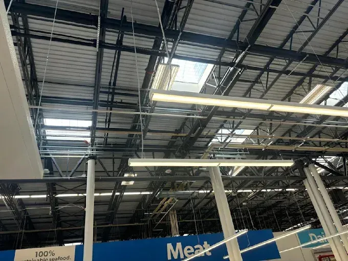 View of a commercial building ceiling with skylights and fluorescent lighting.