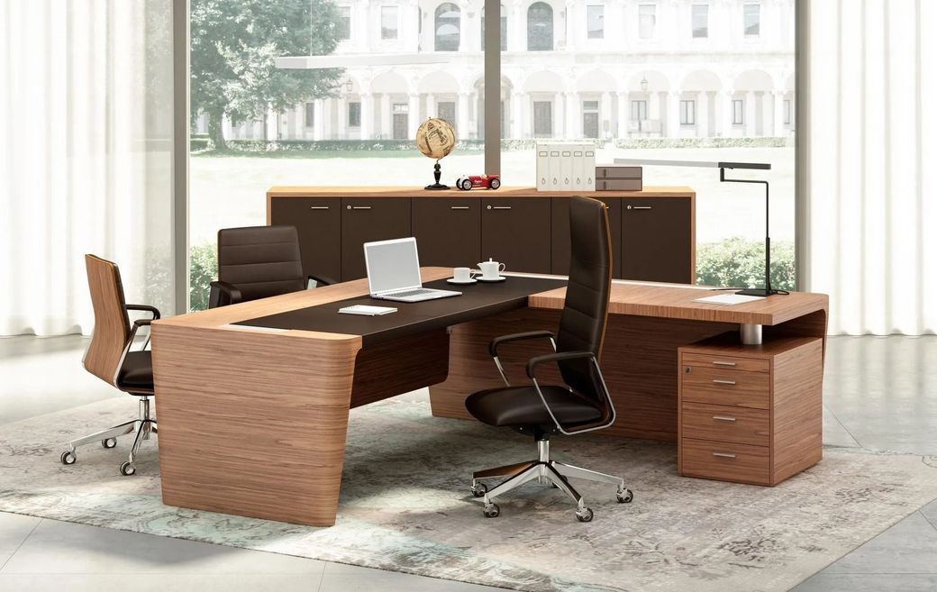 Set da scrivania moderna per ufficio con finiture in legno, laptop, sedia e tappeto davanti a grandi finestre