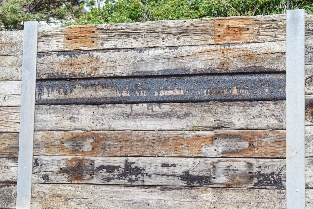 Weathered Wooden Wall With Metal Supports — NQ Prefab Concrete Products Pty Ltd in Port Douglas, QLD