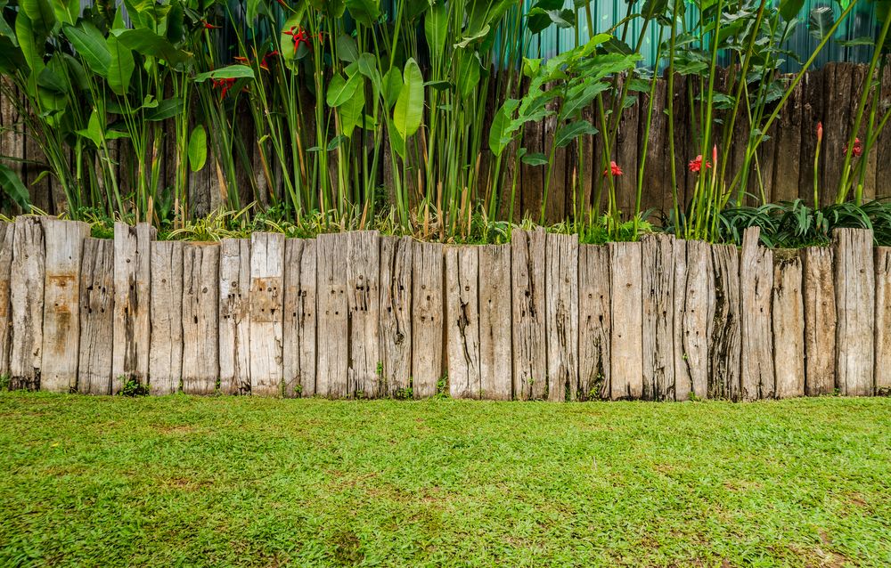 Wooden Fence With Lush Green Plants — NQ Prefab Concrete Products Pty Ltd in Mission Beach, QLD
