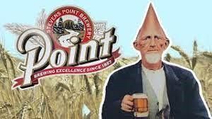 A person with a cone-shaped head holds a beer mug in a field, next to the Stevens Point Brewery logo.