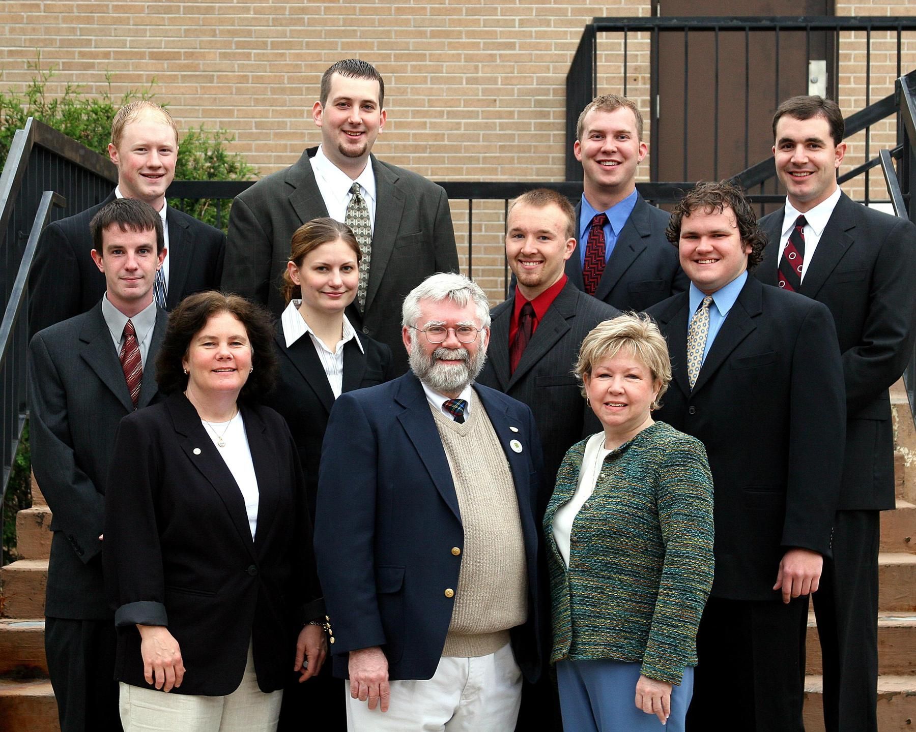 A group of eleven people in professional attire posing for a photo on a set of outdoor concrete stairs.