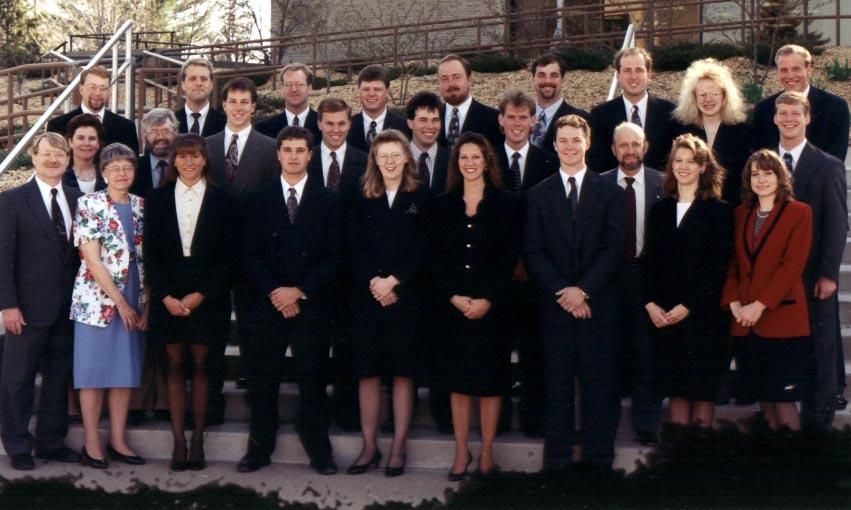 A large group of people in business formal attire standing on outdoor steps for a portrait.