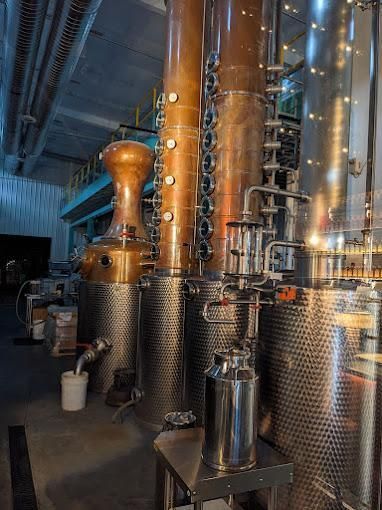 Copper and stainless steel industrial distillation columns inside a manufacturing facility.