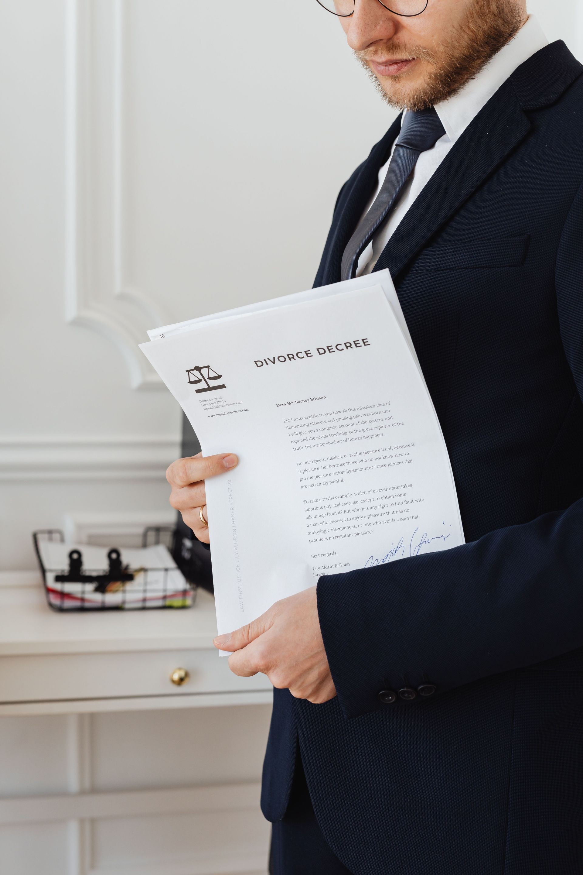 Man in a dark suit holding a white document in a bright room