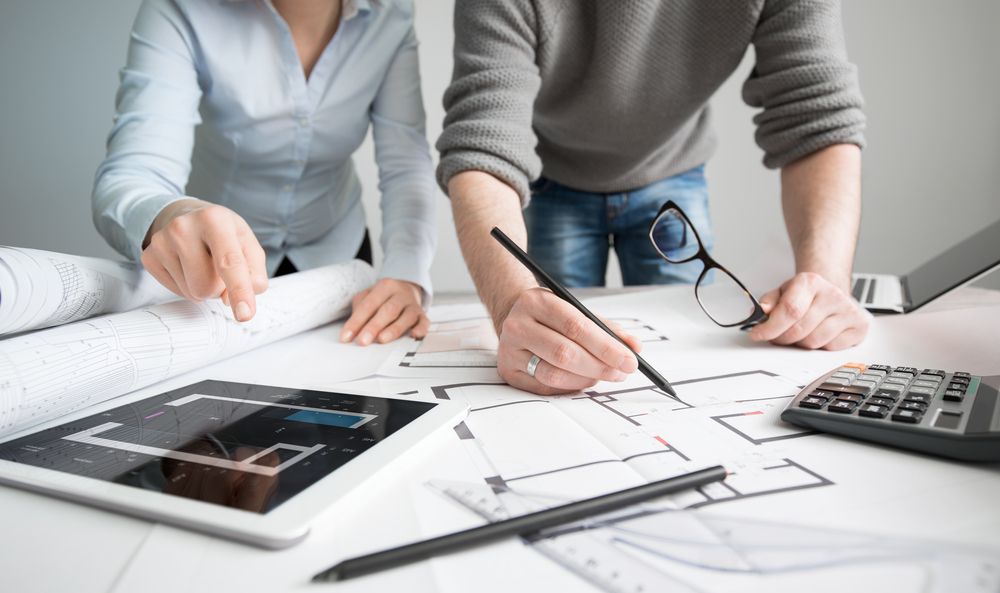 Two People Working on Architectural Blueprints, Using a Tablet — Adamson Town Planning in Noosaville, QLD