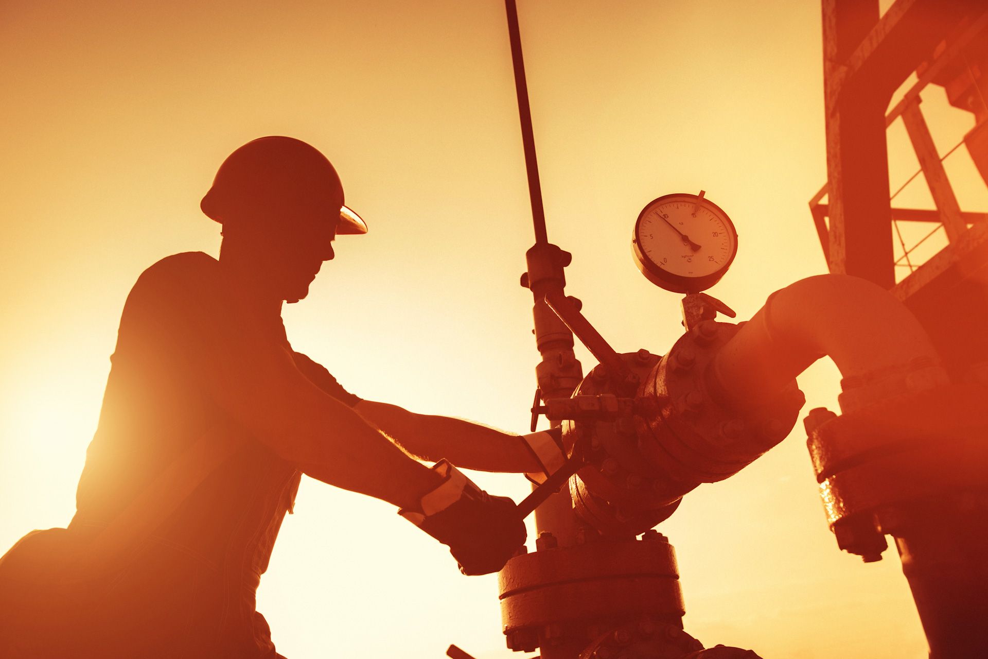 A man is working on an oil rig at sunset
