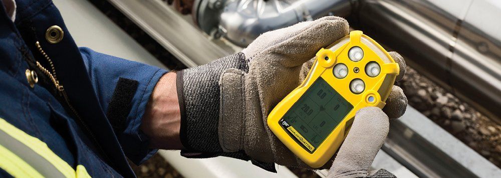 A person wearing gloves is holding a yellow device in their hand