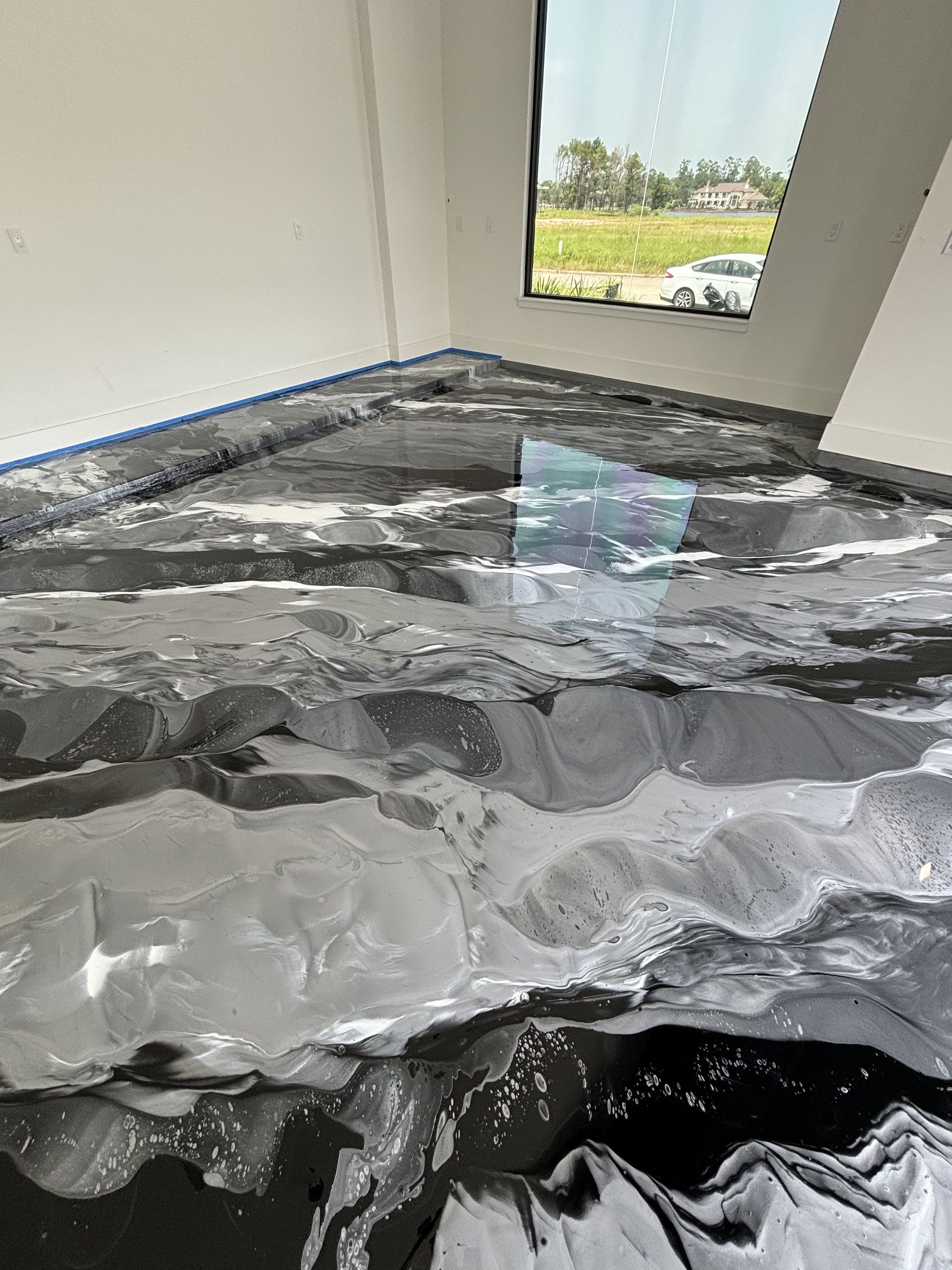 Epoxy floor with marbled black and gray swirls; room with window overlooking a field.