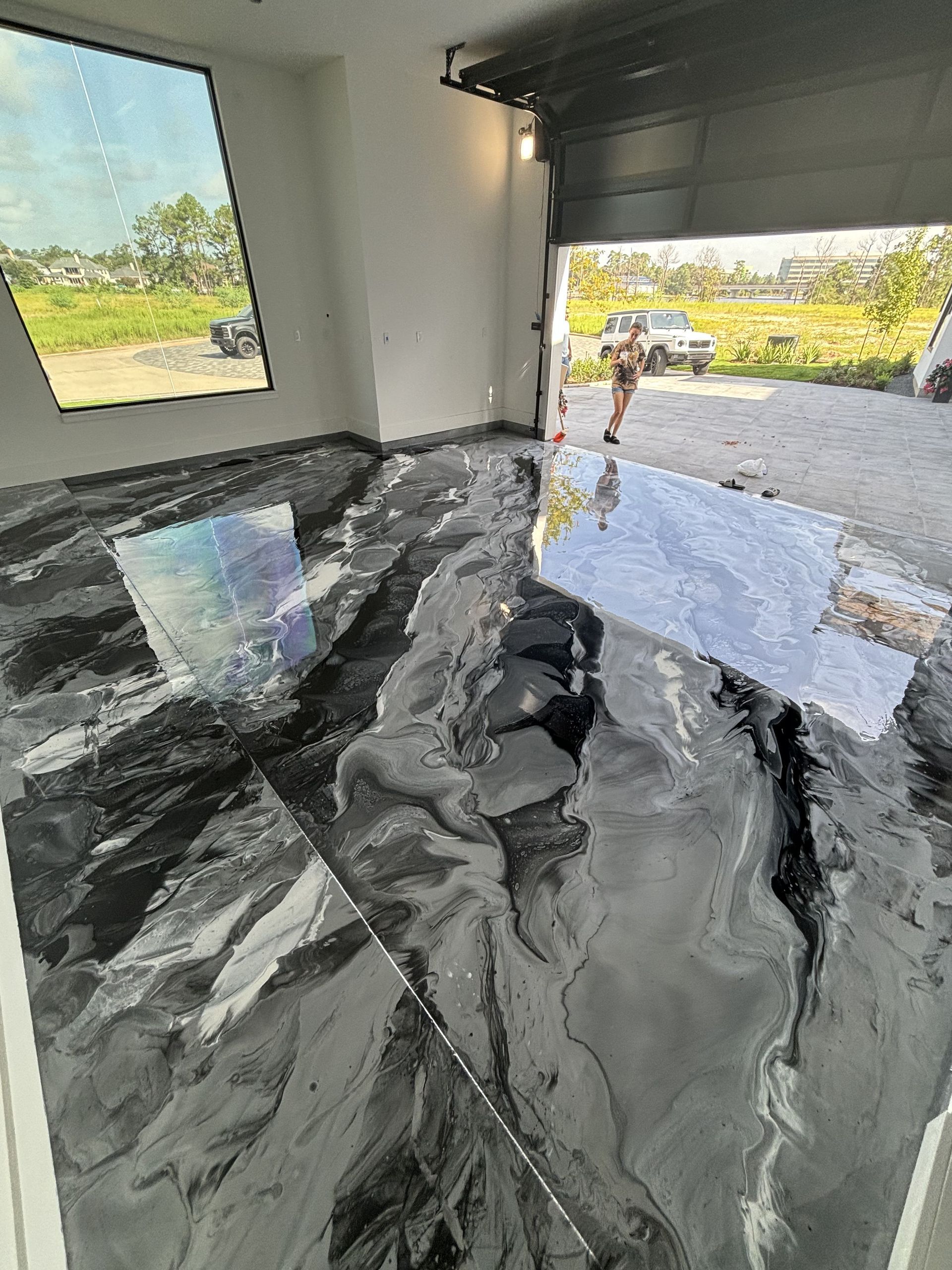 Glossy, epoxy-coated floor in black and silver, with reflection of outdoor view.